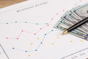 Business charts with dollar, pen on wooden background